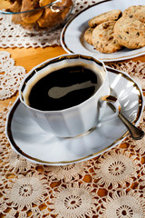 A cup of coffee, lace doily, wooden table, rustic style. Selective focus