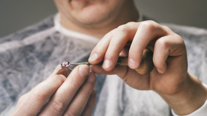 Jeweler fixes stones in a gold ring, close-up