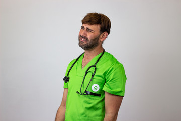 Portrait of male veterinary doctor in green uniform with brown hair crying, facing forwards and looking at the horizon. Isolated on white background.