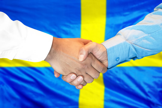 Business handshake on Swedish flag background. Men shaking hands and Swedish flag on background. Support concept