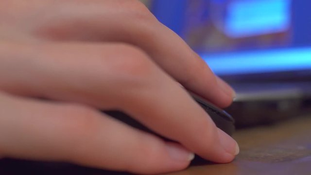 Girl with beautiful hands searches on the Internet via computer and scrolling with a computer mouse.