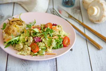 The concept of proper nutrition, keto diet, paleo diet. Salad with fresh vegetables and avocado, baked chicken breast with mushrooms and boiled egg on a pink plate, next to cutlery