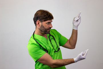 Portrait of male veterinary doctor in green uniform with brown hair making devil horns with one...
