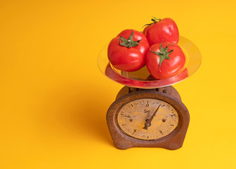 tomatoes on scales on yellow background