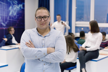 Students life on the campus.Portrait of male college student smiling and looking at camera during class in the classroom. University male american student standing  in classroom.