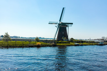 Fototapeta na wymiar Waterways of North Holland with boats and view on traditional Dutch mill, spring landscape