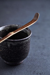 Ceramic tea cup and Chashaku Matcha spoon. Symbolic image. Asian culture. Dark stone background. Close up. Copy space. 