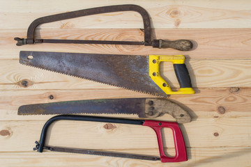 Four handsaws on a wooden table.