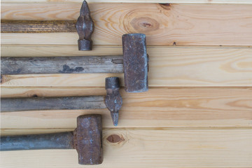 Old sledge-hammers of different size on a wooden table.