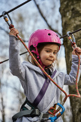 Fototapeta na wymiar Adorable little girl in helmet in rope park in forest