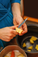 Woman cutting to peel potatoes. Kitchen working