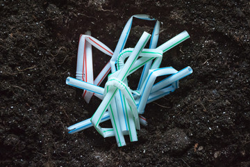 Broken plastic coffee straws buried in the ground