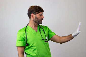Portrait of male veterinary doctor in green uniform with brown hair making a stop sign with a hand,...