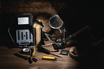 Retro analog voltmeter, soldering iron, book, microcircuit chip, pliers and screwdriver in the...