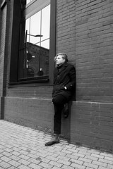 Obraz premium young blond guy standing against the wall leaning on one leg