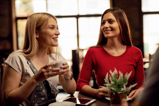 Happy women having fun while drinking coffee in a cafe.
