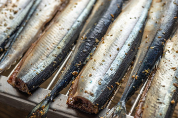 Raw saury on a grill for smoking with lemon and herbs top view