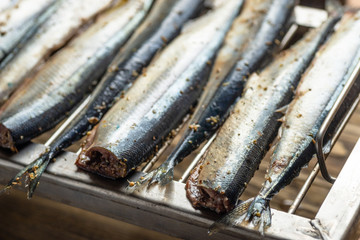 Raw saury on a grill for smoking with lemon and herbs top view