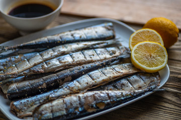Smoked saury on a white dish in the form of fish with lemon and herbs