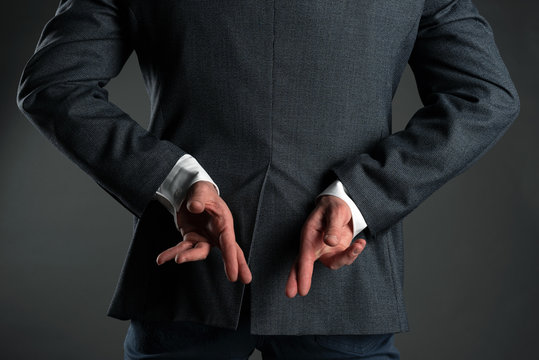The liar business man. A man with crossed finger behind his back is giving a false promises concept. Deceitful person.
