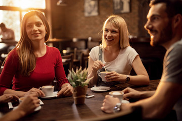 Young happy people drinking coffee and communicating in a cafe.