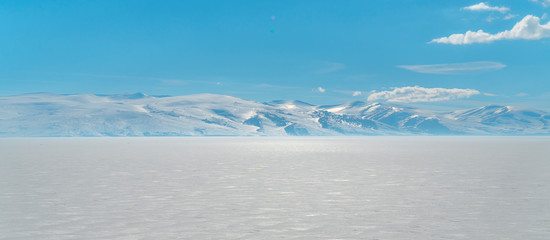 frozen lake with surrounding snow covered rocky mountains 
