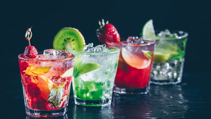 Four colorful tasty alcoholic cocktails in a row at the bar stand. Luxury vacation concept. Place for text. Banner wide screen format