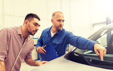 auto service, repair, maintenance and people concept - mechanic checking windshield wiper and man or owner at car shop