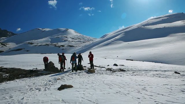 Group of hikers in the snowy mountains. Panoramic shot of Tilicho lake area and high snowy and icy mountains around. Hiking and trekking in Nepal, spring trek around Annapurna mount.