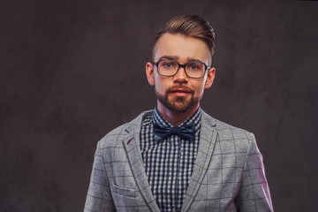 Studio shoot of smart attractive man in checkered blazer, glasses and shirt with bow.