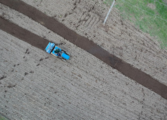 Obraz premium small tractor ploughing in the field. aerial view, agriculture
