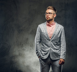 Obraz premium Studio shoot of styilish attractive man in checkered suit, glasses and pink shirt. He put one hand to his pocket.
