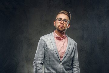 Studio shoot of proud young man in checkered blazer, glasses and pink shirt.