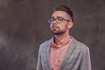 Studio shoot of proud young man in checkered blazer, glasses and pink shirt.
