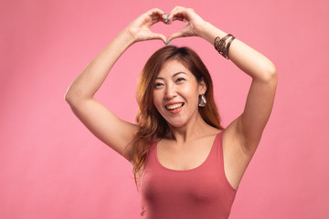 Fototapeta premium Young Asian woman gesturing heart hand sign.