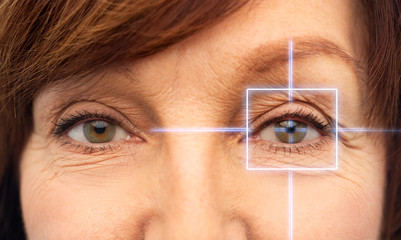 vision, eye surgery and security concept - eyes of senior woman with laser light