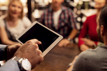 Close up of waiter taking orders on touchpad in a cafe.