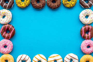 Traditional american donuts of different flavors frame on blue background flat lay mockup