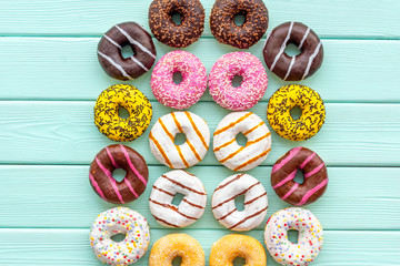 Traditional american donuts of different flavors on mint green wooden background flat lay