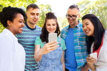 friendship, technology and international concept - group of friends with smartphone at summer park