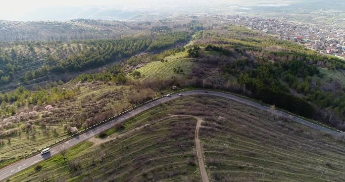 4K areal view of stunning mountain road through green forest. Apuseni Mountains. Winding road in the forest and traffic cars. View from above