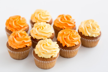 food, pastry and confectionery concept - cupcakes with buttercream frosting over white background