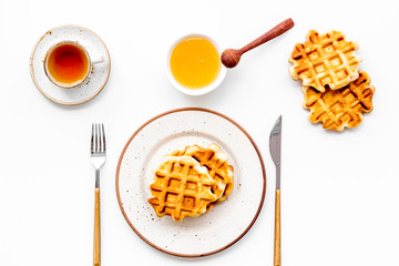 Traditional belgian waffles with honey and tea on served white table background top view