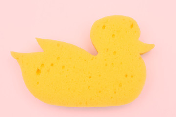 Yellow duck sponge on a pink background. view from above. baby bath sponge.