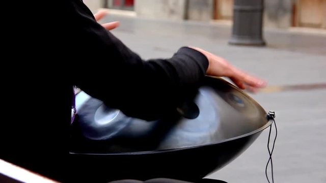 Street musician playing hang drum. Hands of man performing outdoors unique instrument. Art, free concert concepts