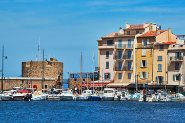 Sailboats and yachts moored to the quay port of Saint-Tropez, France.
