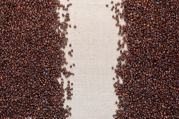 Roasted coffee beans on linea canvas with space in the middle.