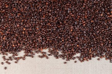 Roasted coffee beans on linea canvas with small space on the bottom.