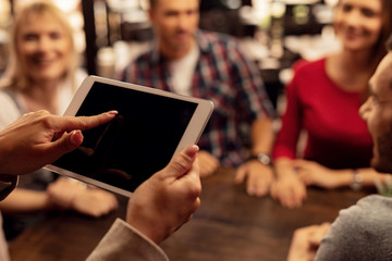 Close up of female waiter using digital tablet while taking orders in a cafe.