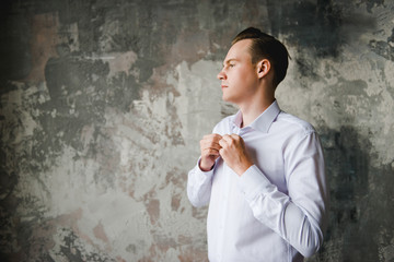 Morning of the groom. Groom morning preparation. Young and handsome groom getting dressed in a wedding shirt